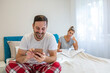 © Dragana Gordic - Young attractive couple in relationship problem with internet mobile phone gambling addict boyfriend ignoring sad neglected and bored girlfriend at home bed feeling depressed and lonely