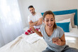 Jealous boyfriend. Shocked man looking at girlfriends mobile phone. A young husband is angry at his wife for constantly using her phone in bed.