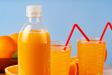 Bottle of orange juice and fresh oranges on table