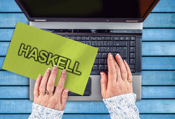 Poster - Haskell programming language. Word Haskell on paper and laptop