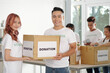 © DragonImages - Young Asian couple working as volunteers in donation center, theay are packing boxed for people in need