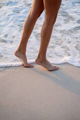 Female legs while walking on the beach by the water