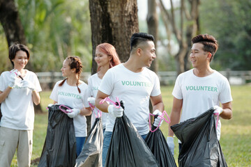 Poster - Young men and women picking up trash when cleaning city park