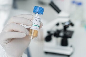 Wall Mural - Cropped view of scientist in latex glove holding coronavirus vaccine in laboratory