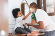 Cheerful African American Man and little boy having fun laughing with shaving foam on their faces in bathroom at home together.