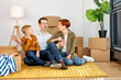© Roman - Portrait Of Friendly Parents With Son Sitting On Floor With Unpacked Cardboard Boxes On Moving Day