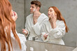 © Roman - adorable caucasian couple take care of facial skin, woman applying cream while man is going to shave stubble