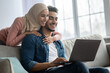 © Prostock-studio - Woman in hijab hugging her handsome husband with laptop