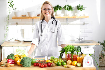 Wall Mural - Professional dietitian in medical suit posing at camera, healthy food vegetables and fruits on table