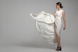© Alena - fashion woman in long white flying dress. Gray background