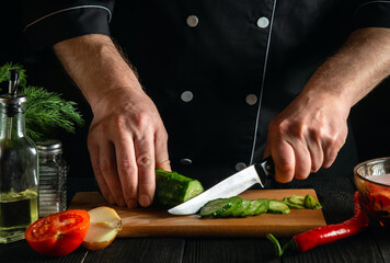 Canvas Print - Chef cutting green cucumber in kitchen in the restaurant. Making delicious salad with fresh vegetables