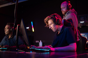 Wall Mural - During the Dota 2 tournament, two guys from the team play at the computers, the coach watches from behind