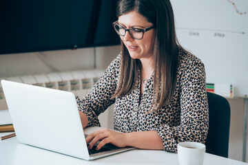 Wall Mural - Happy woman working on laptop from home office. 
Cheerful woman working from home using laptop computer for video conference call meeting with colleagues during the coronavirus shutdown