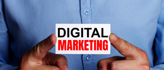 Fototapete - The words DIGITAL MARKETING is written on a white business card in a man's hands. Business concept