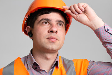 Wall Mural - portrait of young construction worker in hard hat on grey studio background, face of successful engineer