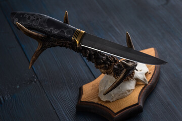 Handmade hunting knife made of Damascus steel lies on the horns