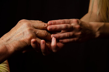 Old and young hands close up. Respect for the elderly. Grandmother's wrinkled hands. The granddaughter touches the wrinkles on the old hands of the grandmother. Young and old hands together. Force