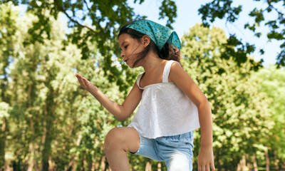 a cute little girl playing and dancing in the park on a sunny day. kid having cozy summer picnic wit