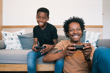 Father and son playing video games together at home.