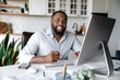 © Kateryna - Portrait of a confident successful African American businessman, real estate agent, lawyer or manager, wearing a stylish shirt, working remotely at the computer, looking at camera, smiling friendly