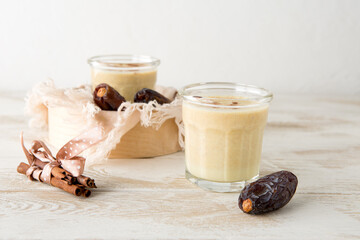 Wall Mural - glasses with a milkshake with dates and cinnamon on a light table