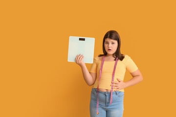 Wall Mural - Shocked overweight girl with measuring scales on color background