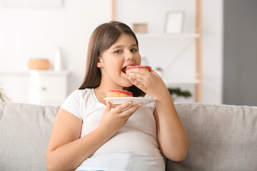 Wall Mural - Overweight girl eating unhealthy doughnuts at home