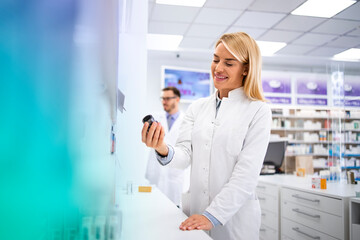 Wall Mural - Female pharmacist working in pharmacy store taking medicine from the shelf.