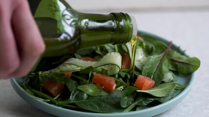 Wall Mural - A man pours olive oil on a salad. Healthy vegan food, close-up