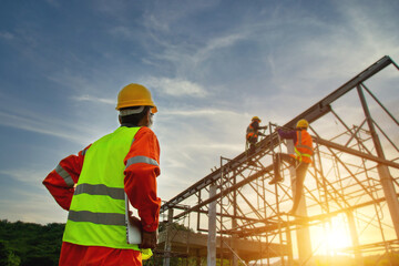 Asian construction worker control in the construction of roof structures on construction site and sunset background