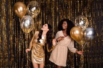 Poster - Photo of two optimistic brunette curly hairdo ladies with balloons look empty space wear dress isolated on gold color background