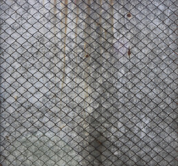 metal net of grids over a weathered gray plank with rusty grooves in the background - industrial pattern