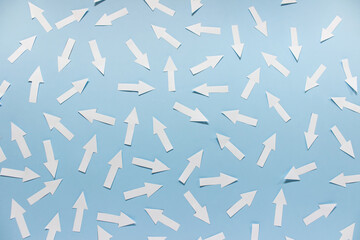 concept of chaos randomly arranged many white paper arrows on blue background.