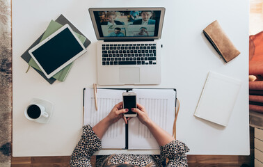 Wall Mural - Table top view of businesswoman working at home using laptop and phone for video conference call meeting with colleagues during the coronavirus shutdown