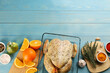 Raw chicken, orange slices and other ingredients on light blue wooden table, flat lay. Space for text