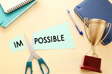 Poster - man hand holding card with the text impossible, cutting the word im so it written possible. success and challenge concept