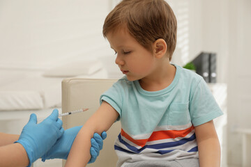 Nurse vaccinating little boy in clinic. Immunization concept