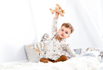 young boy plays with a wooden airplane in the children's room