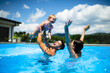 © Halfpoint - Young family with small daughter in swimming pool outdoors in backyard garden, playing.