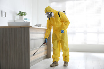 Wall Mural - Employee in protective suit sanitizing office. Medical disinfection