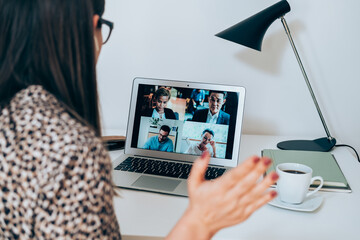 Wall Mural - Close up of businesswoman talking on video call meeting with colleagues. Back view of business woman discuss with clients or coworkers at web conference using a laptop and bluetooth earphones at home