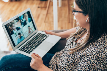 Wall Mural - Close up of businesswoman talking on video conference meeting with colleagues online on laptop computer. Multi-ethnic business team using laptop and bluetooth earphones for teleconferencing from home