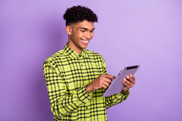 Wall Mural - Photo of charming positive afro american man look read tablet good mood smile isolated on purple color background