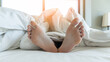 © Chinnapong - Sleeping comfort, health relaxation, bedtime insomnia and world sleep day concept with young girl bare foot on bed lying lazy, resting in comfy hotel bedroom on white bed sheet