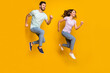 © deagreez - Full length body size view of attractive cheerful motivated couple jumping running isolated over bright yellow color background
