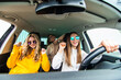 © F8  \ Suport Ukraine - Three female friends in sunglasses enjoying traveling in the car.