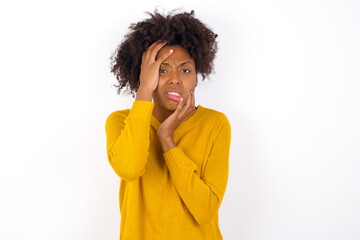 Wall Mural - Young gloomy young beautiful African American woman wearing yellow sweater against white wall , hiding face with hands pouting and crying, standing upset and depressed complaining about job problem.