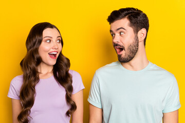 Sticker - Portrait of lovely amazed cheerful couple looking at each other good mood isolated over bright yellow color background