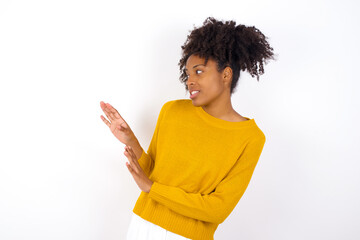 Wall Mural - Displeased young beautiful African American woman wearing yellow sweater against white wall keeps hands towards empty space and asks not come closer sees something unpleasant