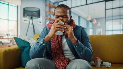Aufkleber - Ill and Tired Black African American Drinking Hot Tea and Calling into Office with Video Call on Laptop from Cozy Living Room. Sick and Nauseous Male in Warm Scarf Talking to Friend Over Live Camera.